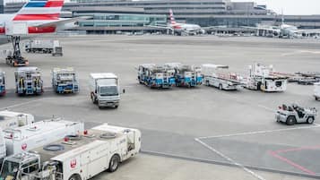 Ein Flughafenterminal mit abgestellten Flugzeugen, Bodenfahrzeugen und dem Flughafengebäude im Hintergrund.