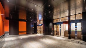 A modern hotel lobby with a spacious open area, glass doors leading to the reception, and a prominent hotel sign. - APA Hotel Ueno Hirokoji (Tokyo)