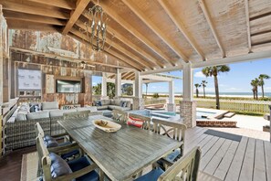Un espace extérieur abrité, doté d’une table et de bancs en bois, d’un téléviseur et offrant une vue sur l’océan.