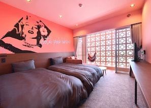 A modern hotel room with a large bed, a small table, and a hammock. - Hotel Pink Hibiscus (Miyakojima)