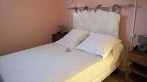 Ein Bett mit weißer Bettwäsche, ein Kopfteil, zwei Nachttische und eine kleine Nachttischlampe.
