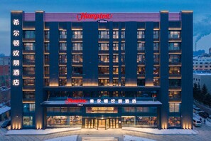 A hotel with a modern facade, multiple floors, and illuminated signage.