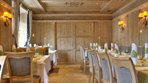 A restaurant with wooden paneled walls, white tablecloths, and green candle holders. - Hotel Zebru (Stelvio)