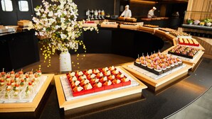 Un buffet proposant une variété de plats et agrémenté d’un grand arrangement floral.