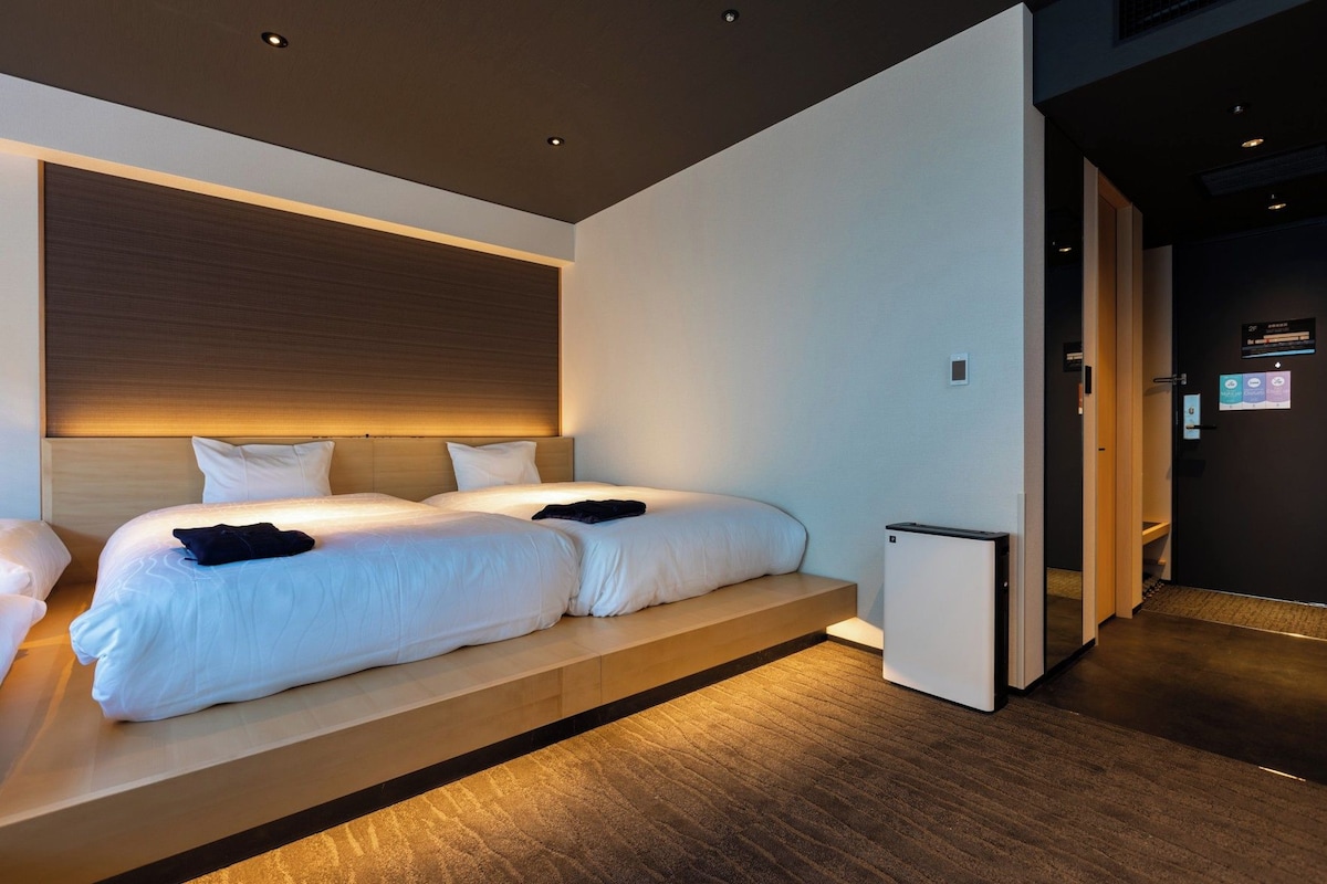 Une chambre d’hôtel moderne avec un grand lit, une petite table de chevet et un radiateur intégré.