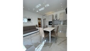 A modern living room with a sofa, dining table, and chairs. - Appartamenti Boschetto (San Michele al Tagliamento)