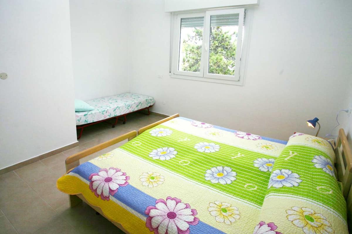 Une petite chambre propre, avec un lit simple, une fenêtre et une table de chevet.
