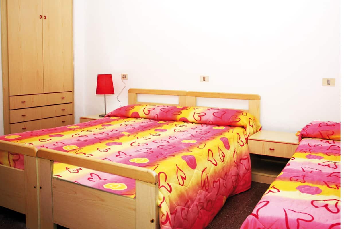 Une chambre à coucher avec un lit en bois, une table de chevet et une armoire.