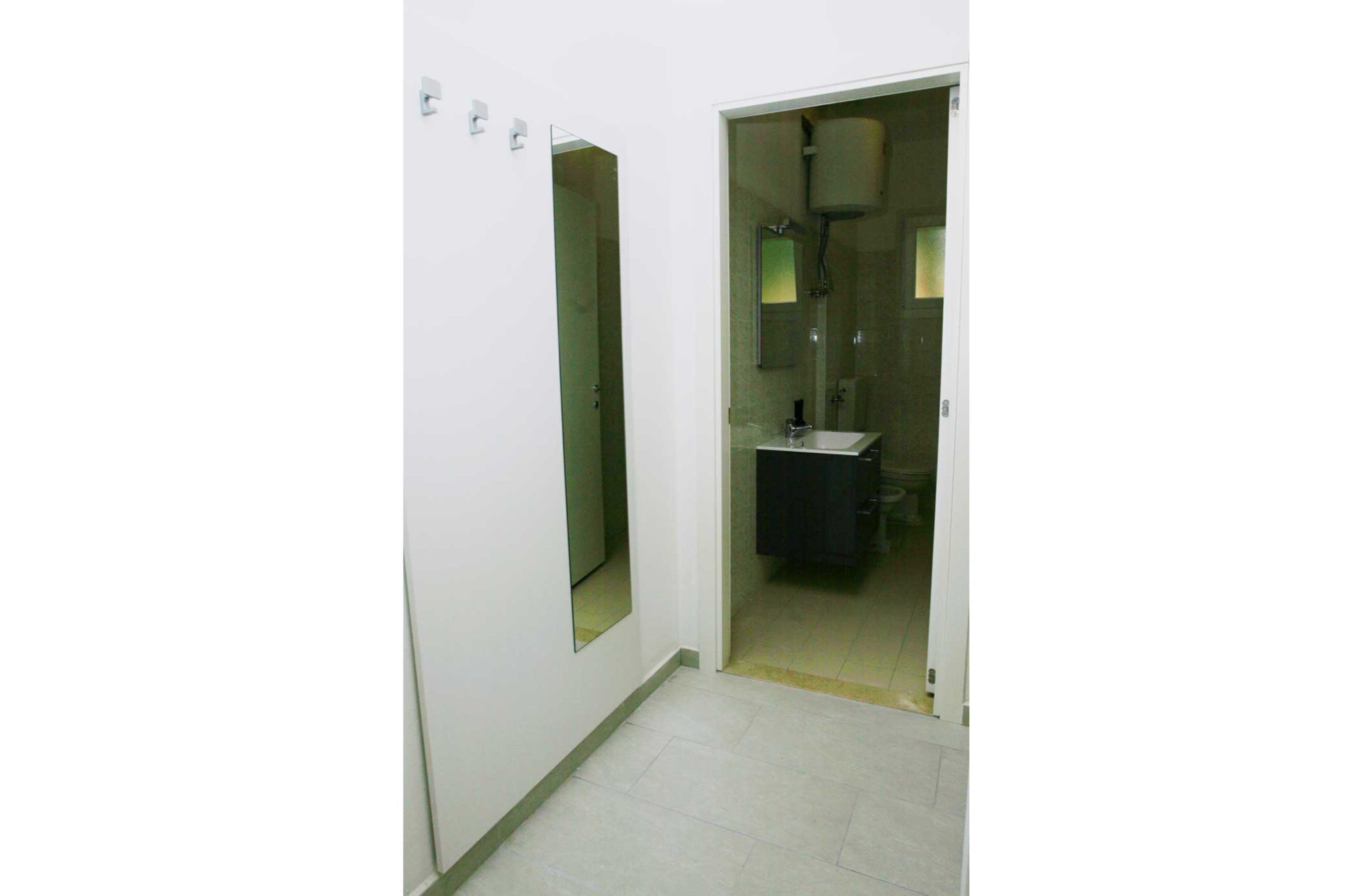 Pasillo que conduce a un baño con lavabo y espejo.