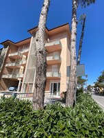 Un edificio a più piani con balconi, un parcheggio e un cielo azzurro limpido.