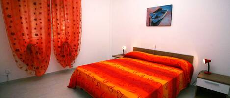 A bedroom with a bed, a nightstand, a lamp, and a painting on the wall.