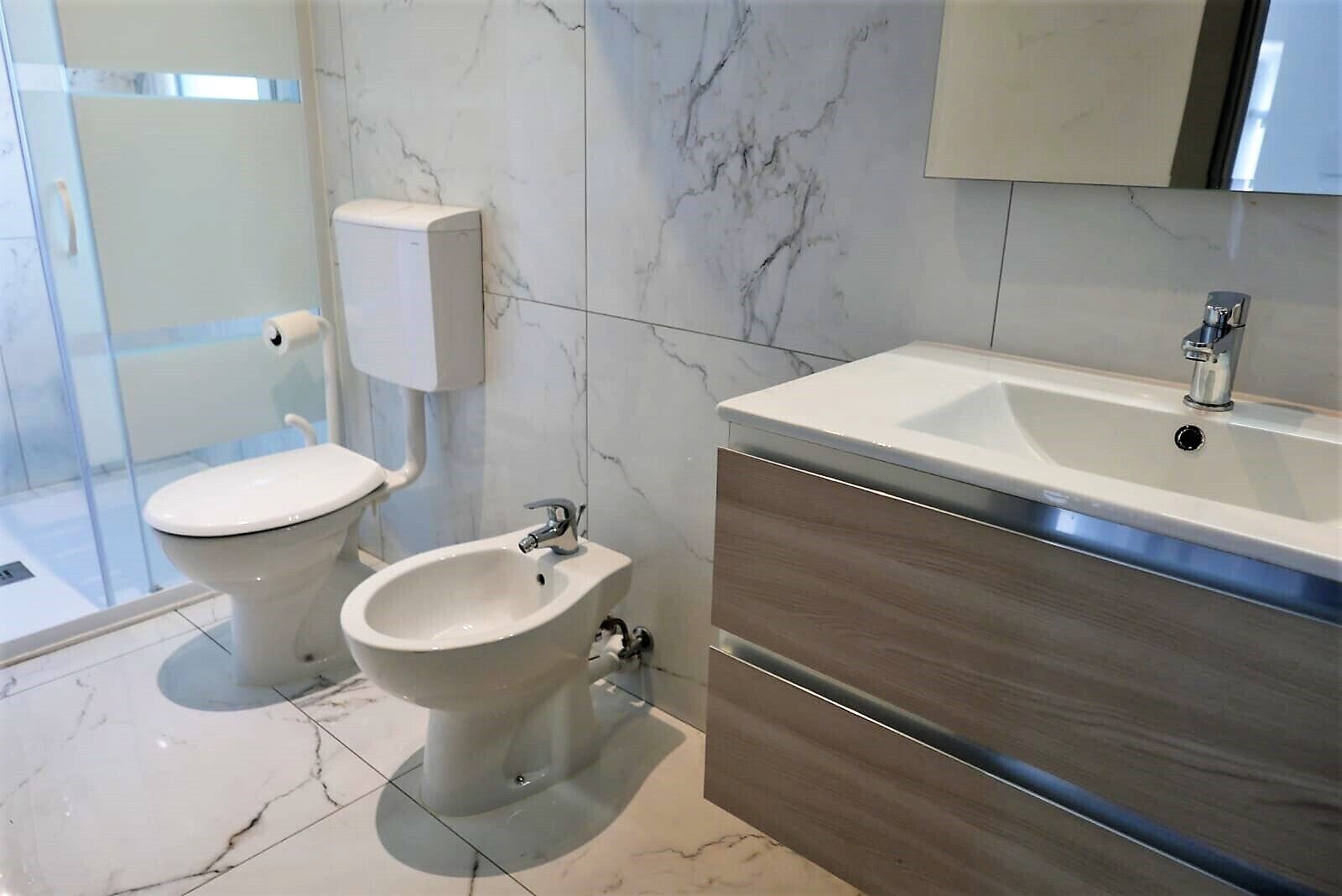 A modern bathroom with a toilet, bidet, and a vanity with a sink.