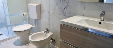 A modern bathroom with a toilet, bidet, and a vanity with a sink.