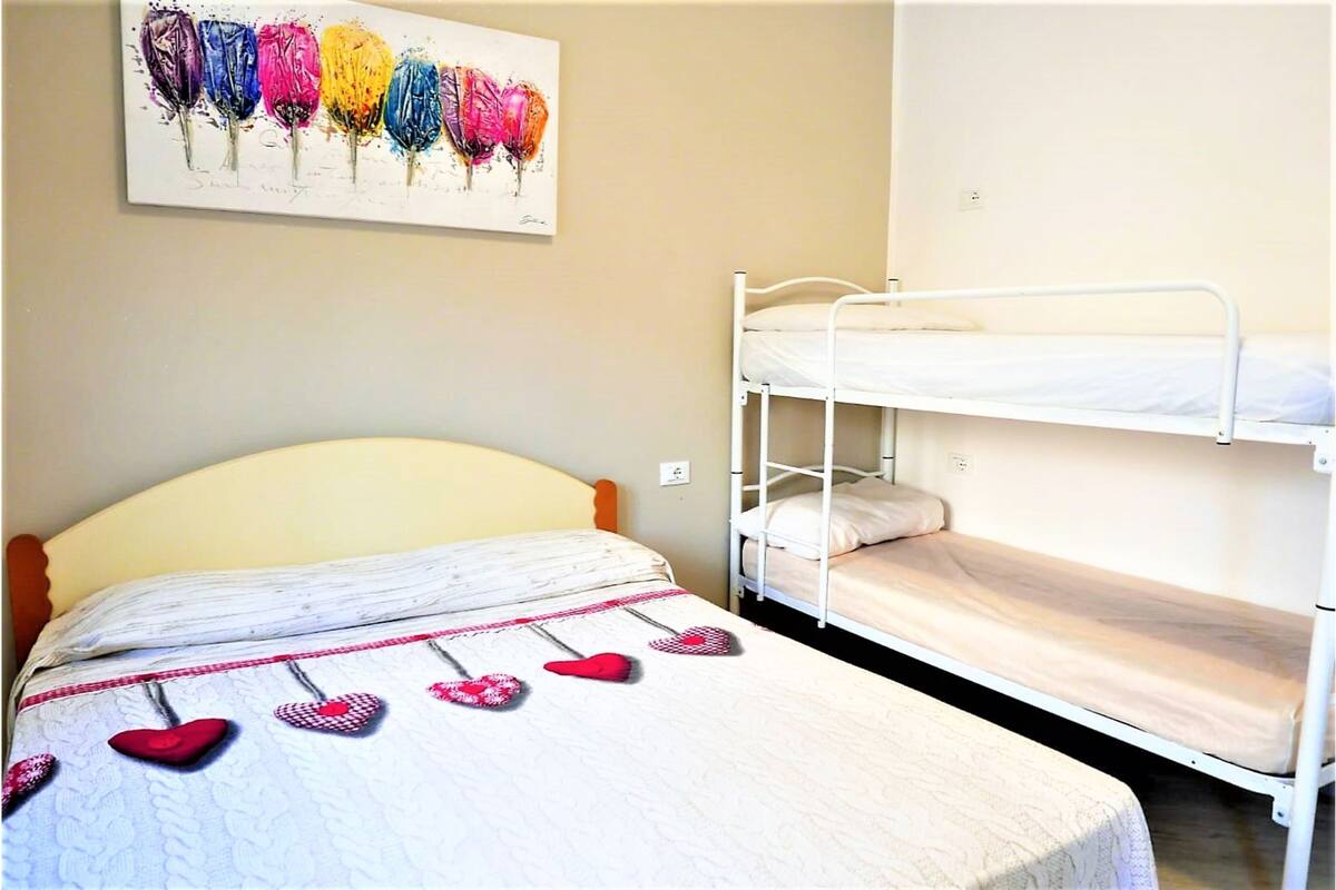 Une chambre avec un lit simple, un lit superposé et une œuvre d’art représentant des ballons, accrochée au mur.