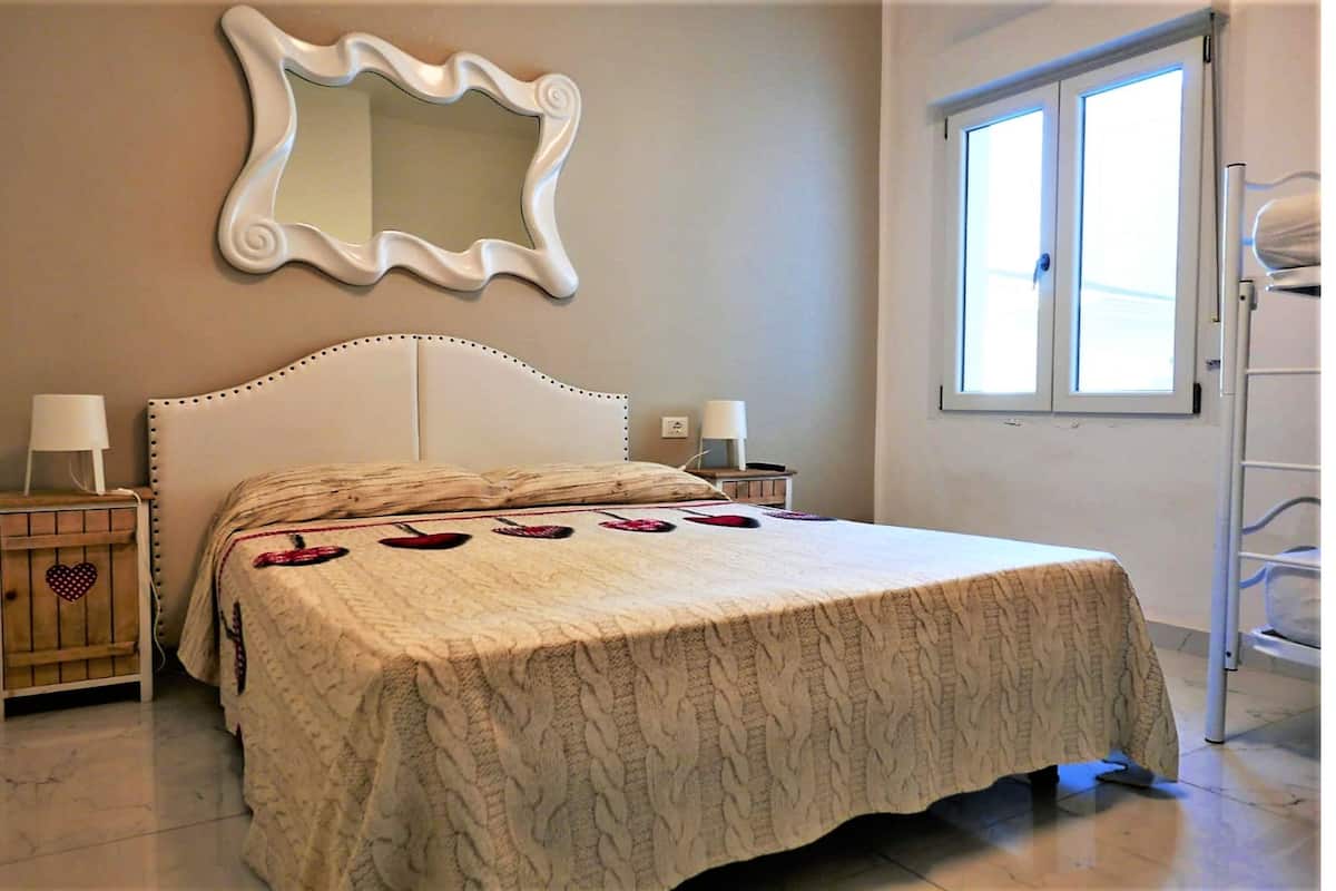 Une chambre avec un grand lit, un miroir, des tables de chevet et une fenêtre.