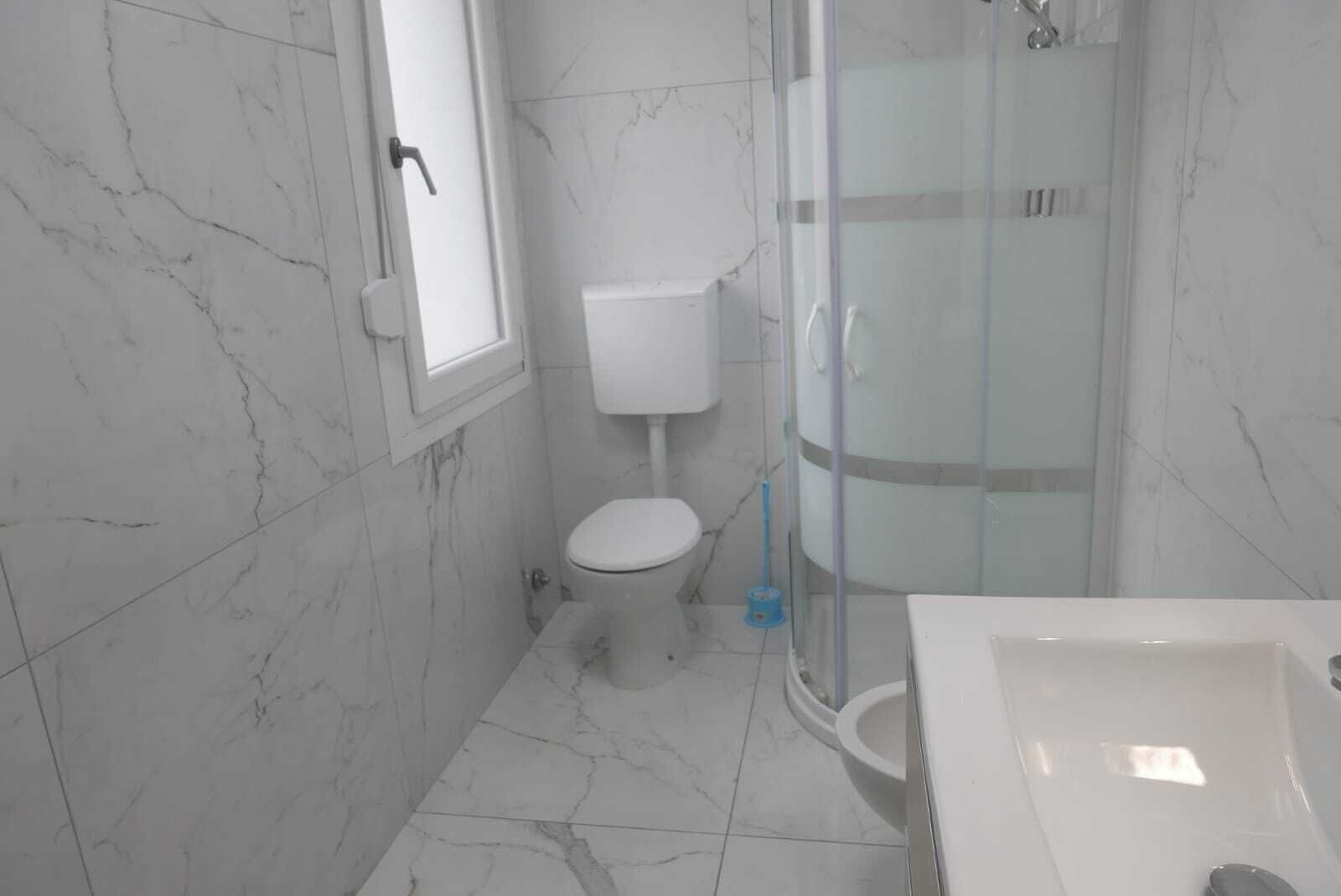 A bathroom with a toilet, a glass-enclosed shower, and a sink.