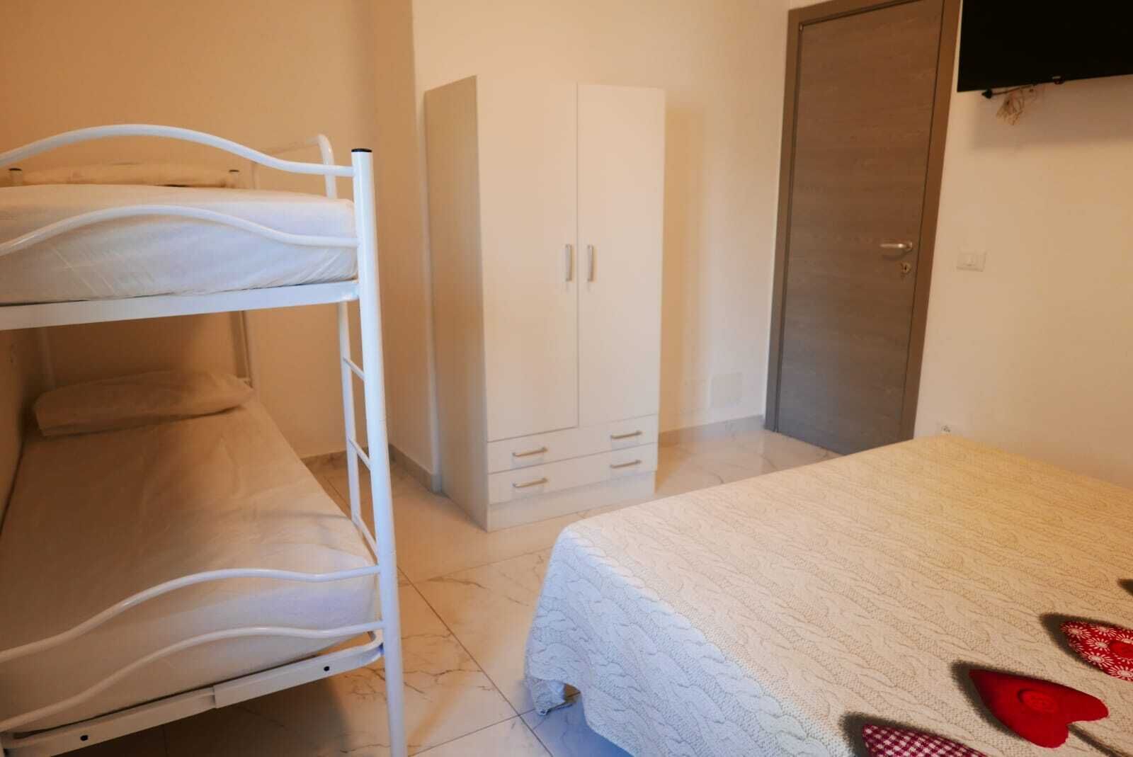 Ein Zimmer mit Etagenbetten, einem Kleiderschrank und einem Bett mit gemustertem Bettbezug.