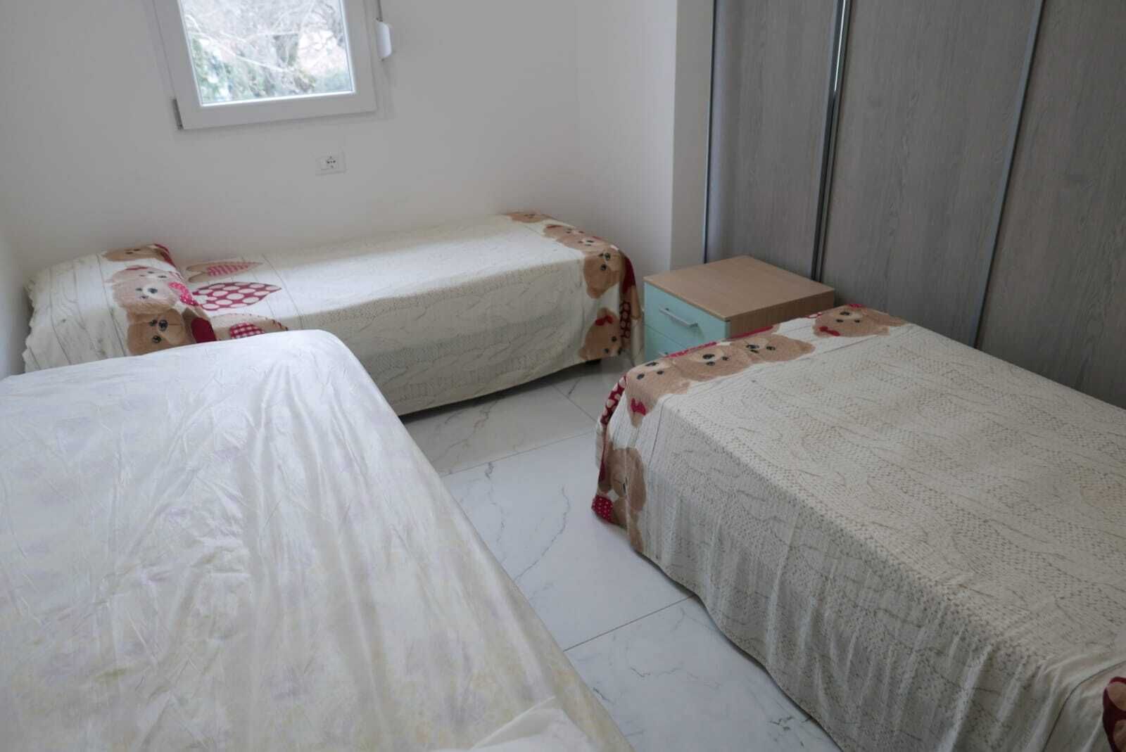Ein Zimmer mit zwei Betten, einem Fenster und einem Kleiderschrank.