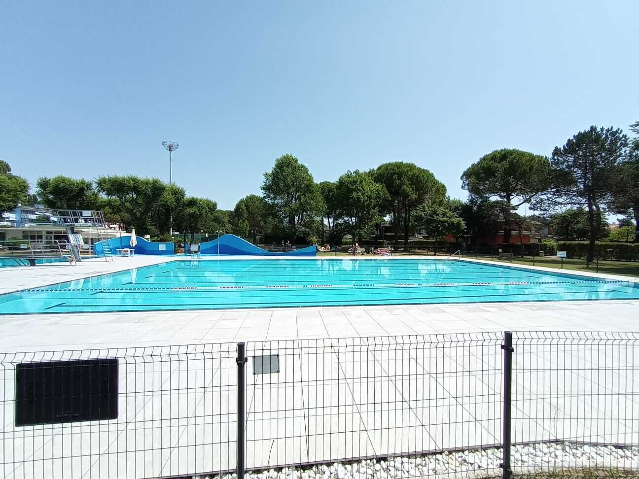 A swimming pool with a tiled deck and a metal fence.