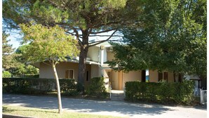 A two-story house with a front porch, a driveway, and a well-maintained lawn. - Appartamenti Olimpia (San Michele al Tagliamento)