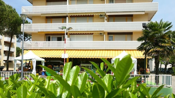 A multi-story building with balconies, a yellow awning, and a small outdoor seating area.