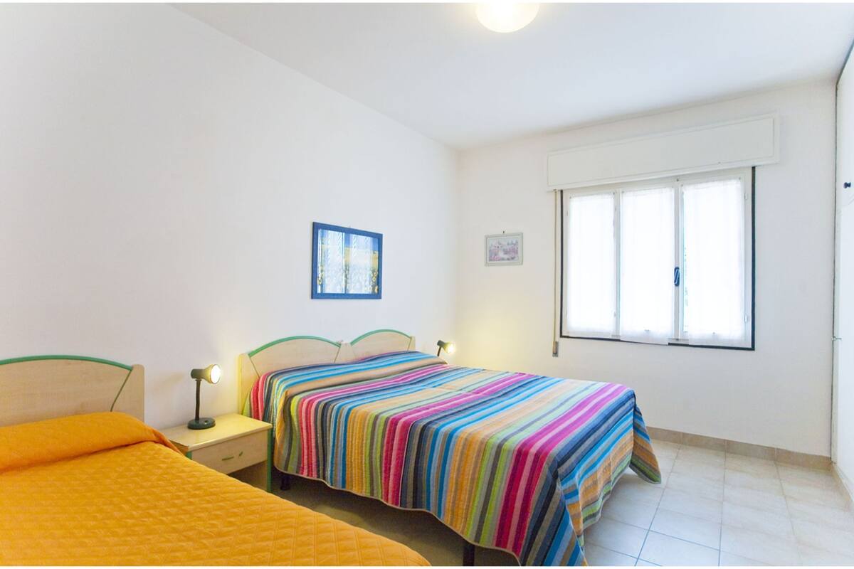 Un dormitorio con dos camas, una ventana y una mesita de noche con lámpara.