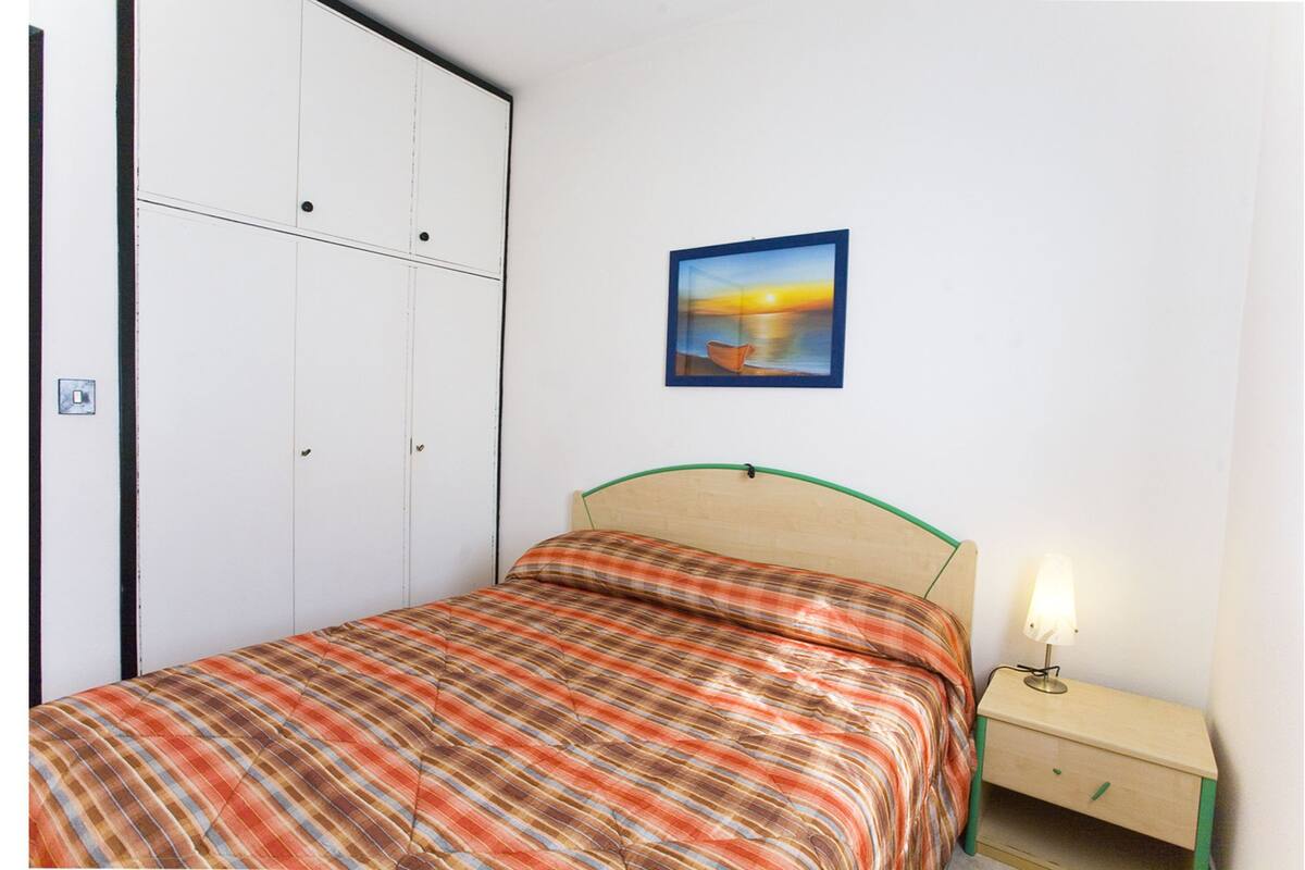 Un dormitorio con cama, mesita de noche, un cuadro en la pared y un armario.