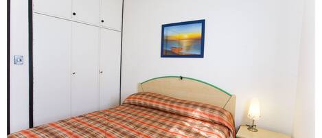 Un dormitorio con cama, mesita de noche, un cuadro en la pared y un armario.