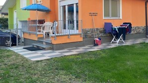 A two-story house with a balcony, a satellite dish, and a small outdoor seating area with a table and chairs. - Villa Polluce (San Michele al Tagliamento)