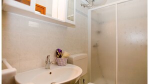 Een badkamer met een wastafel, spiegel en douche.