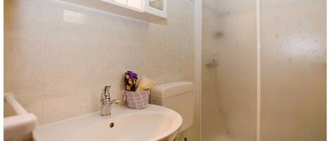 A bathroom with a sink, mirror, and shower.