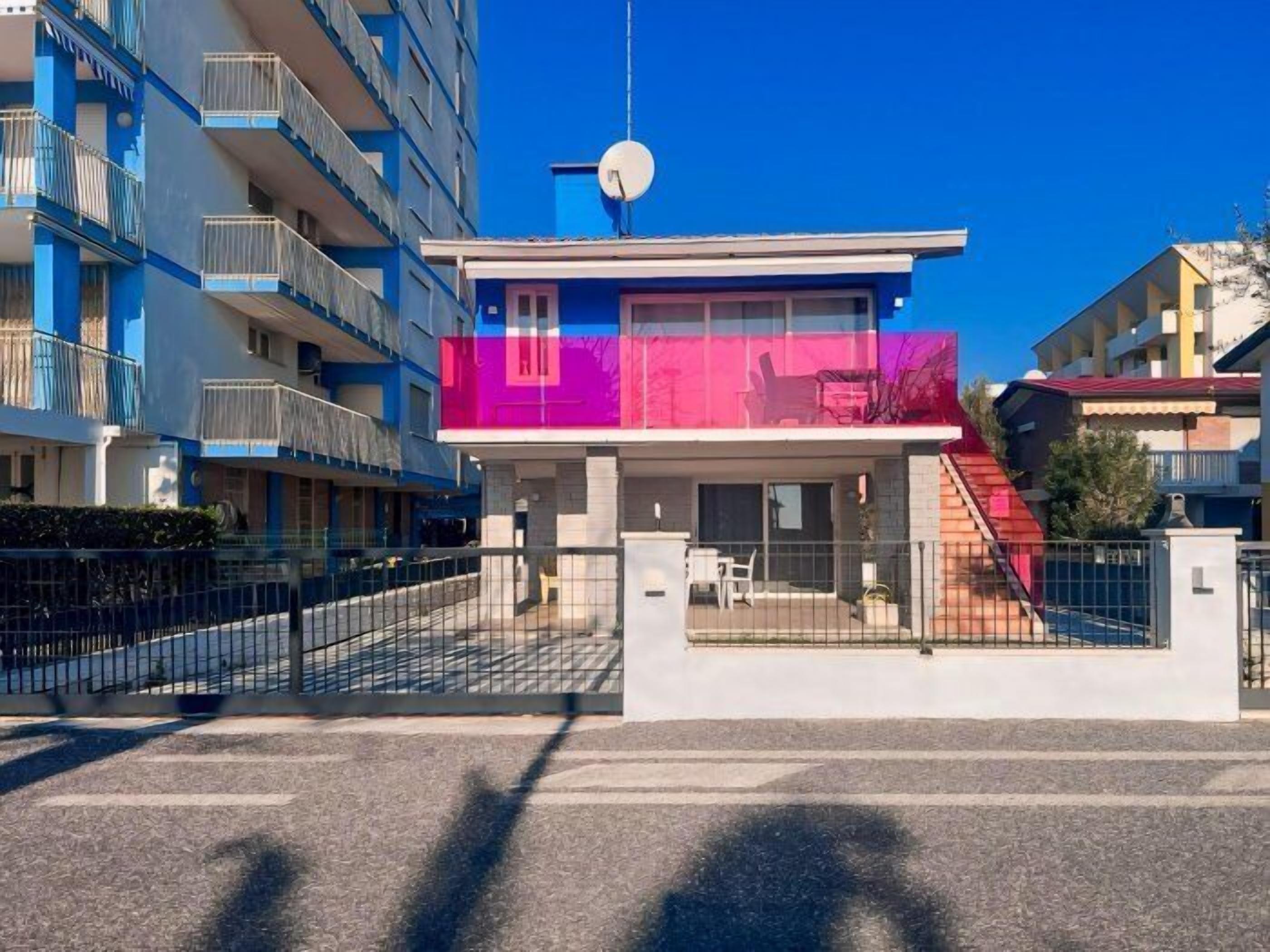 A modern building with a flat roof, a satellite dish, and a gated entrance.