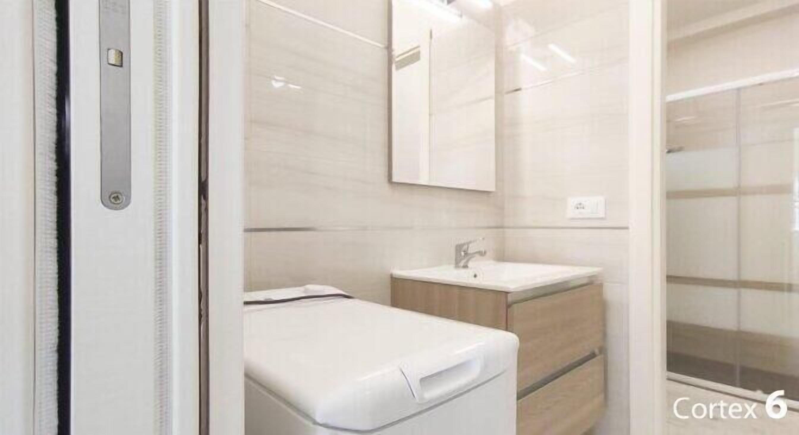 A modern bathroom with a white sink, mirror, and a shower area.