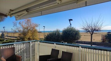 Un balcone con sedie in vimini, vista sulla spiaggia e cielo sereno.