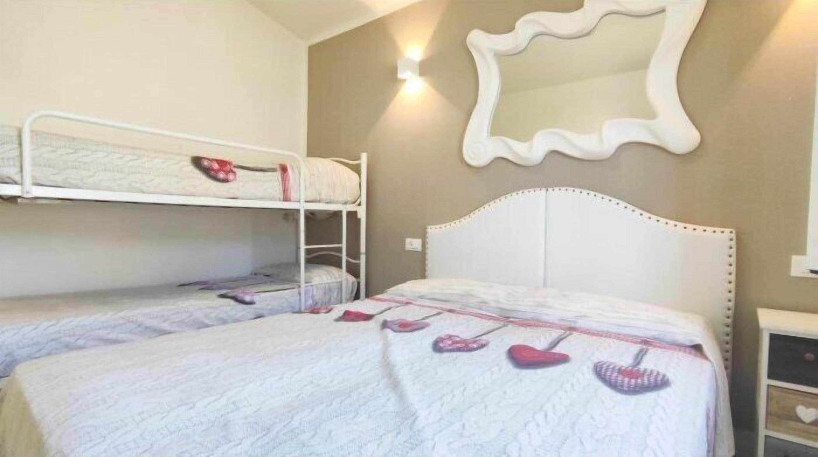 A room with two bunk beds, a large mirror, and a bedside table with a heart-shaped drawer.