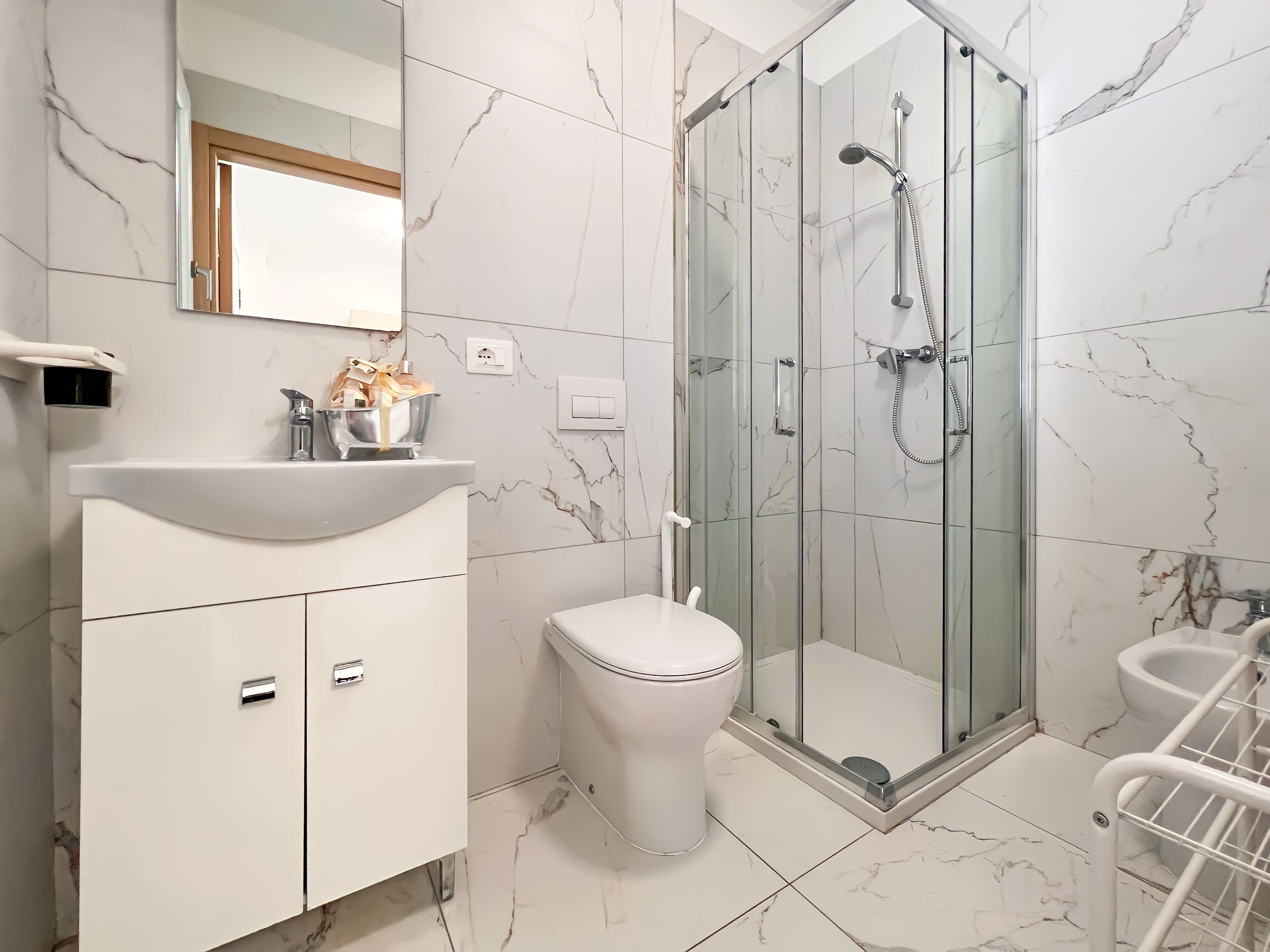 A modern bathroom with a glass-enclosed shower, a white sink, and a toilet.