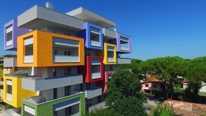 Un immeuble à plusieurs étages, caractérisé par des sections distinctes aux couleurs vives, chacune dotée de balcons et de fenêtres.