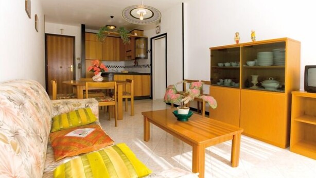 A living room with a sofa, coffee table, and wooden cabinet. - Appartamenti Tiziano (San Michele al Tagliamento)