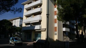 A multi-story building with balconies, a parked car, and a street lamp. - Appartamenti Tiziano (San Michele al Tagliamento)