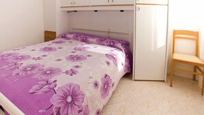 A bedroom with a bed, a chair, and a wardrobe. - Appartamenti Tiziano (San Michele al Tagliamento)