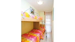 Une chambre avec des lits superposés, chacun recouvert d’une couette aux motifs de cœurs colorés.
