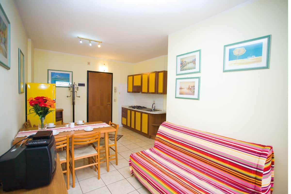 Un espacio habitable compacto con comedor, kitchenette y un sofá colorido a rayas.