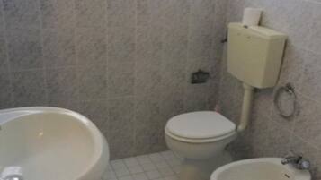Un baño pequeño con inodoro, bidé y lavamanos.