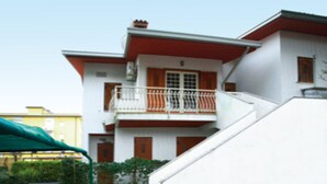 Ein zweistöckiges Gebäude mit weißer Fassade, roten Akzenten und einem Balkon.