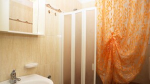 Et badeværelse med en hvid vask, toilet og bruser med et mønstret gardin.