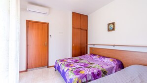 Un dormitorio con cama, armario y un pequeño cuadro en la pared.