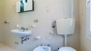 Un baño con lavamanos, bidé, inodoro y un espejo sobre el lavamanos.