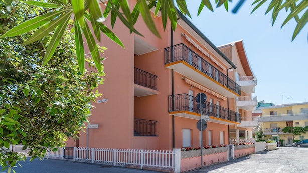 Un edificio de varios pisos con balcones, una cerca blanca y un letrero que dice "Centauro".