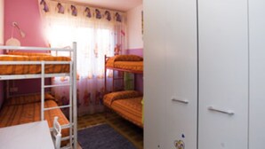 Une chambre avec des lits superposés, un bureau et une armoire.