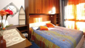 Une chambre à coucher avec un lit, une armoire en bois et une table de chevet ornée d’un vase de fleurs.